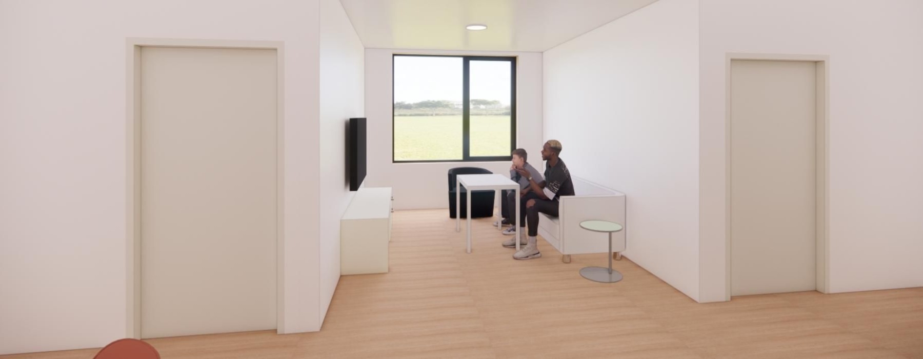 two guys sit on a couch and play video games by a large window